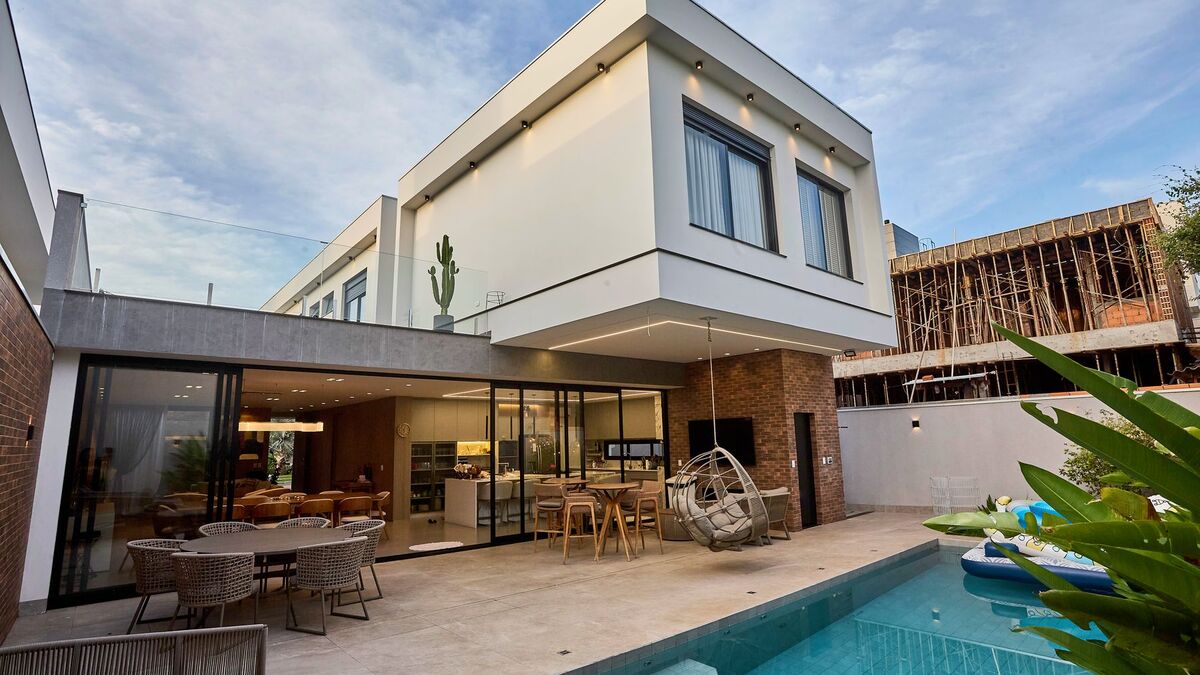 A newly built rectangular pool beside a modern two-story house with a covered patio