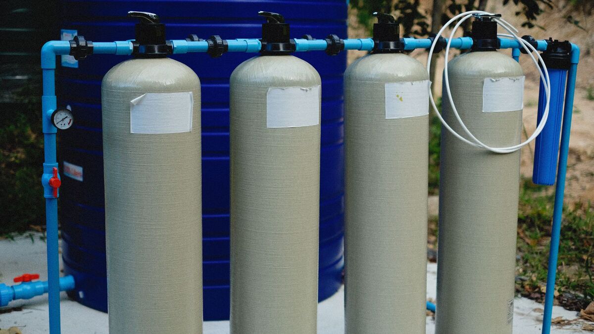 A row of tall water filter tanks plumbed together on an equipment pad